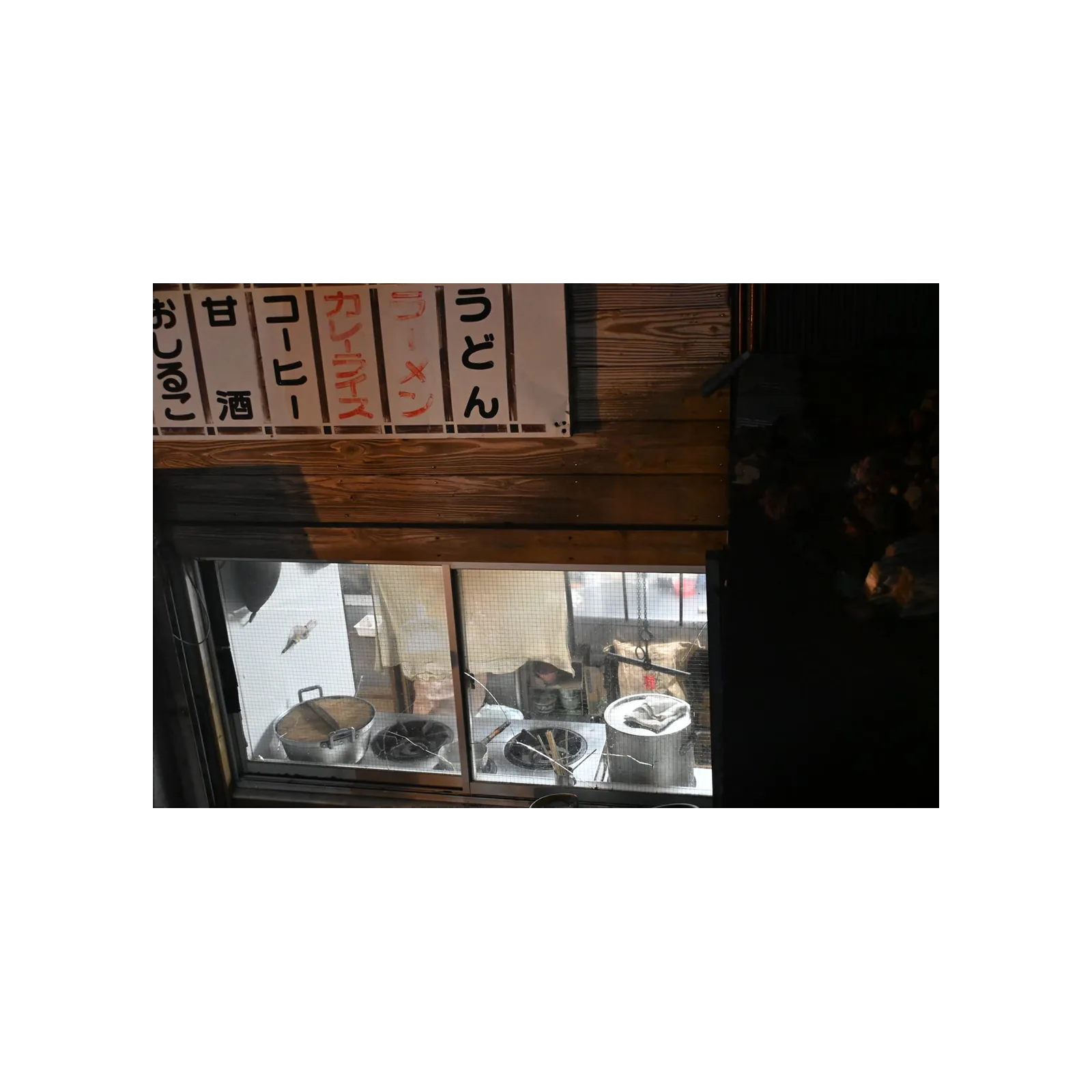 Noodle stand window and hand-painted menu signs at night