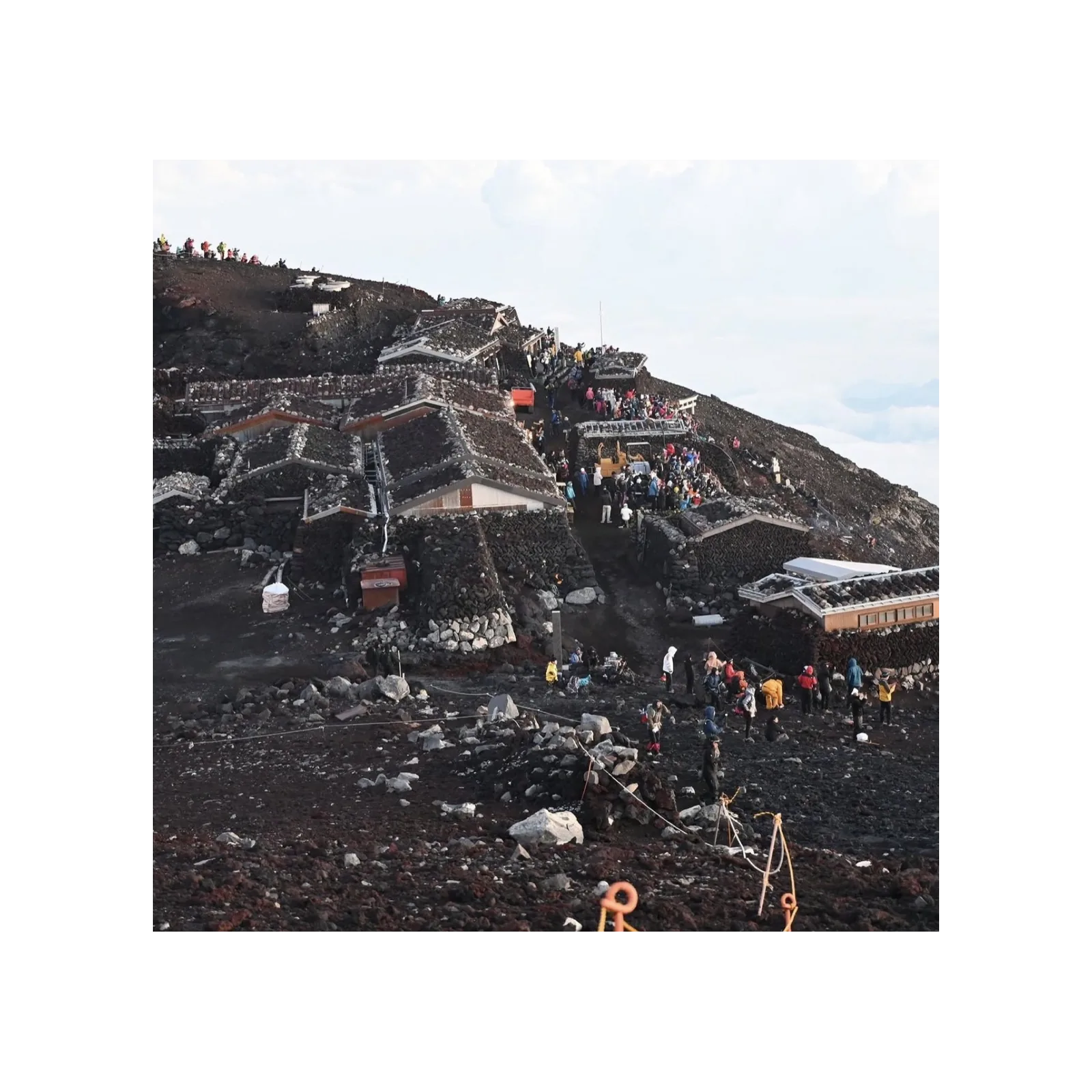 Photograph of climbers among stone huts near the summit of Mount Fuji