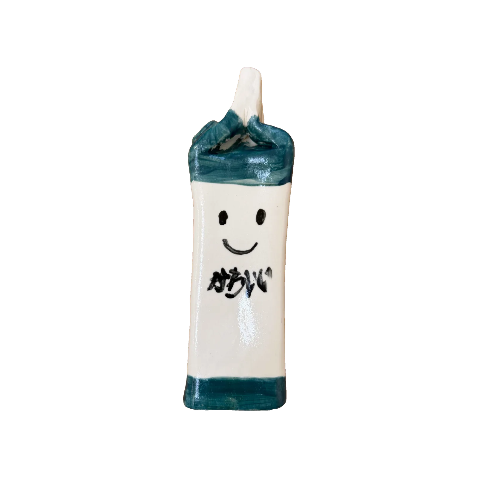 Two ceramic milk cartons side by side, one with a smiling face and Japanese writing, one painted with a dalmatian cow