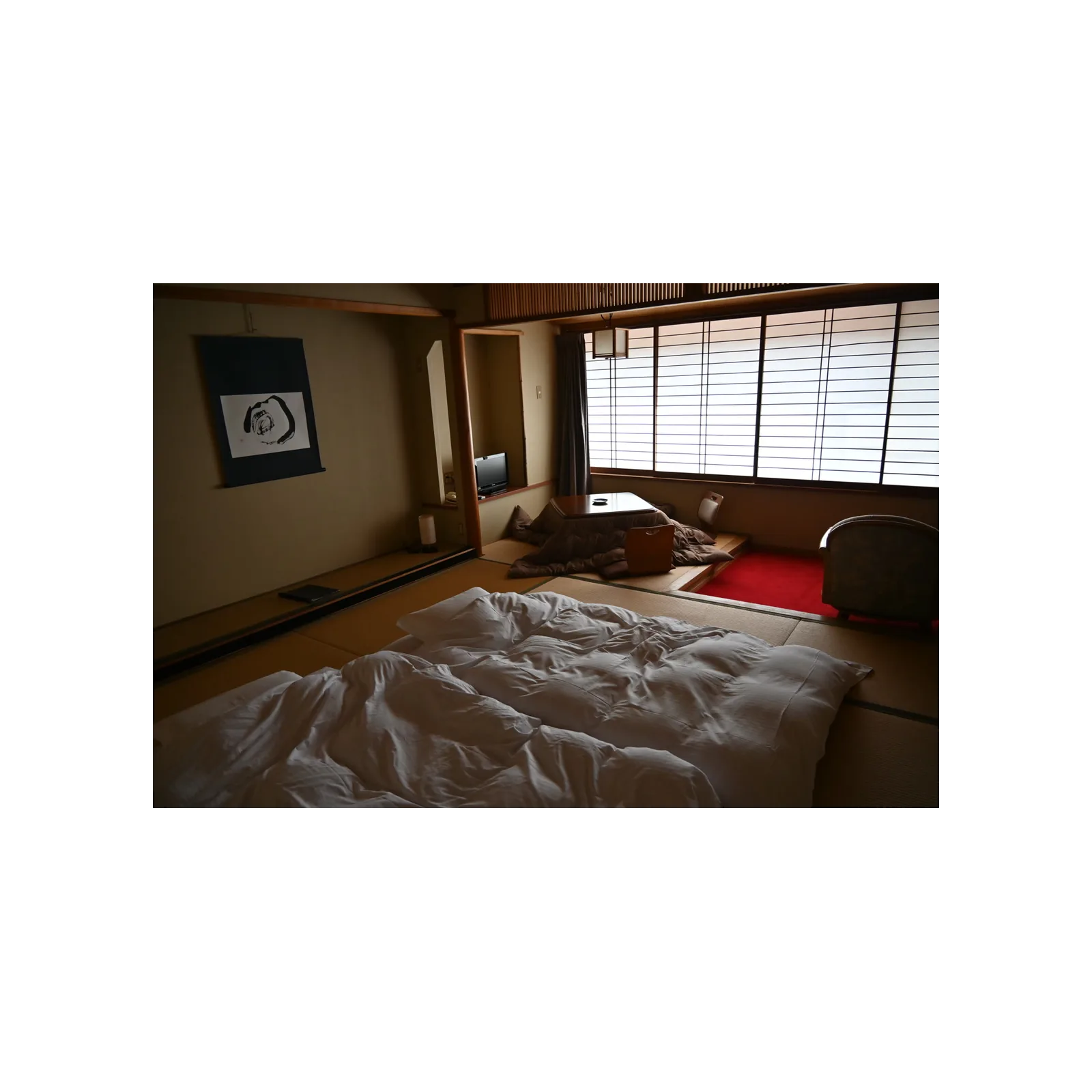 Ryokan room with open futons, a kotatsu, and shoji windows