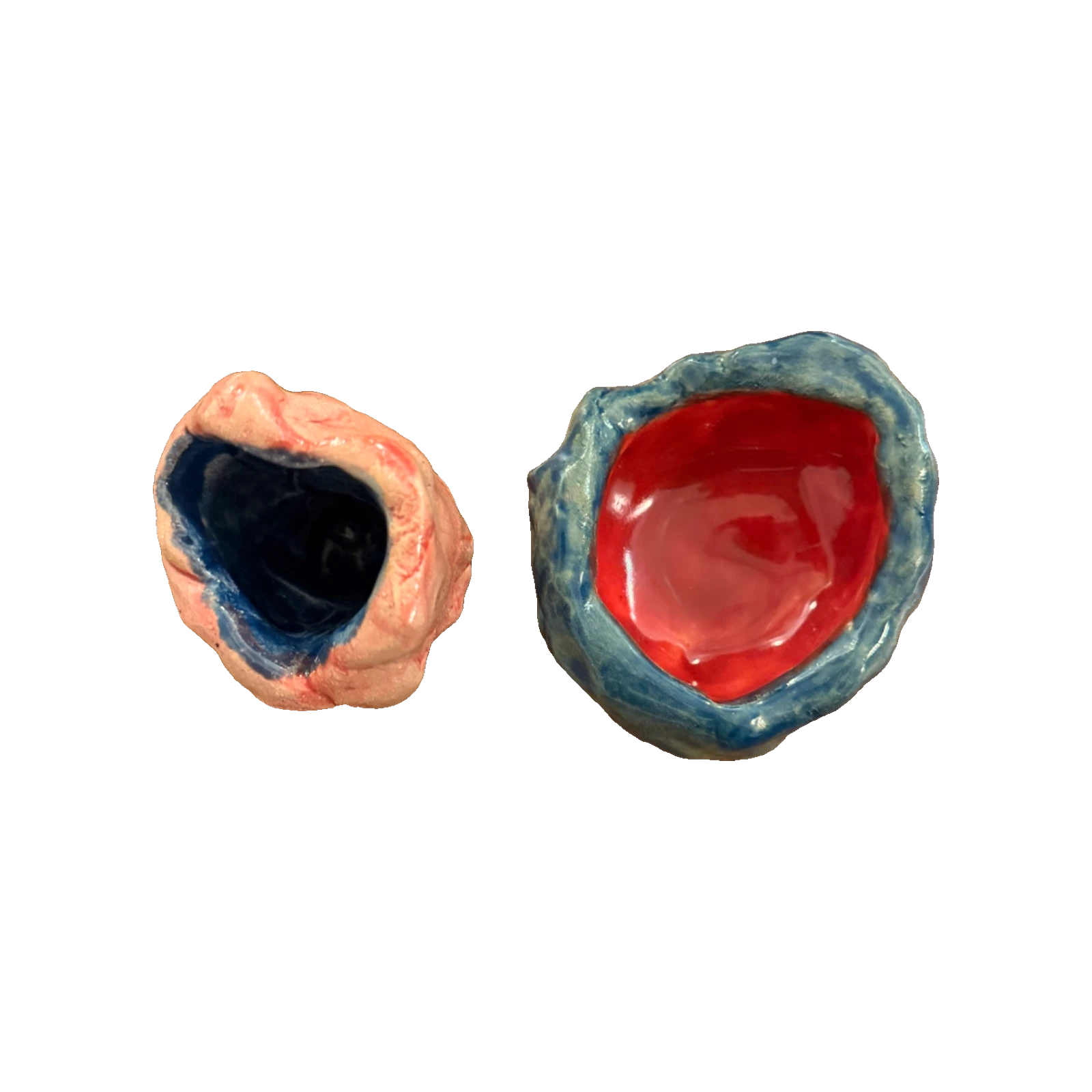 Two small ceramic vessels: one pink with a navy-blue interior, one blue with a red interior