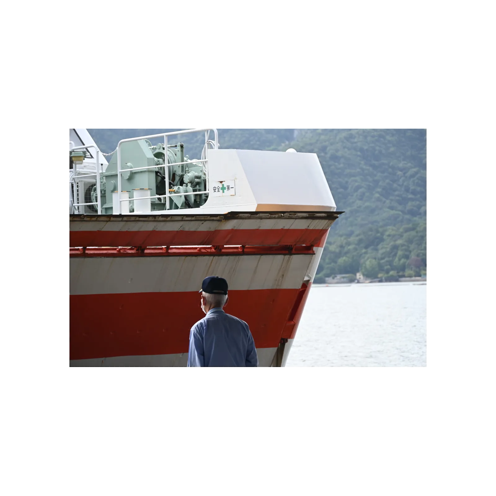 A man in a cap facing the bow of a docking ferry