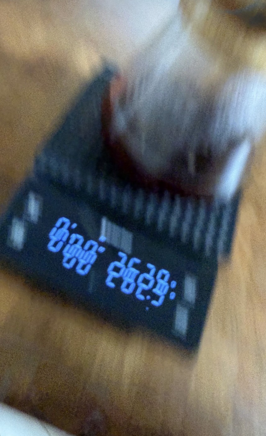 Blurry photograph of a digital display showing strange glowing digits