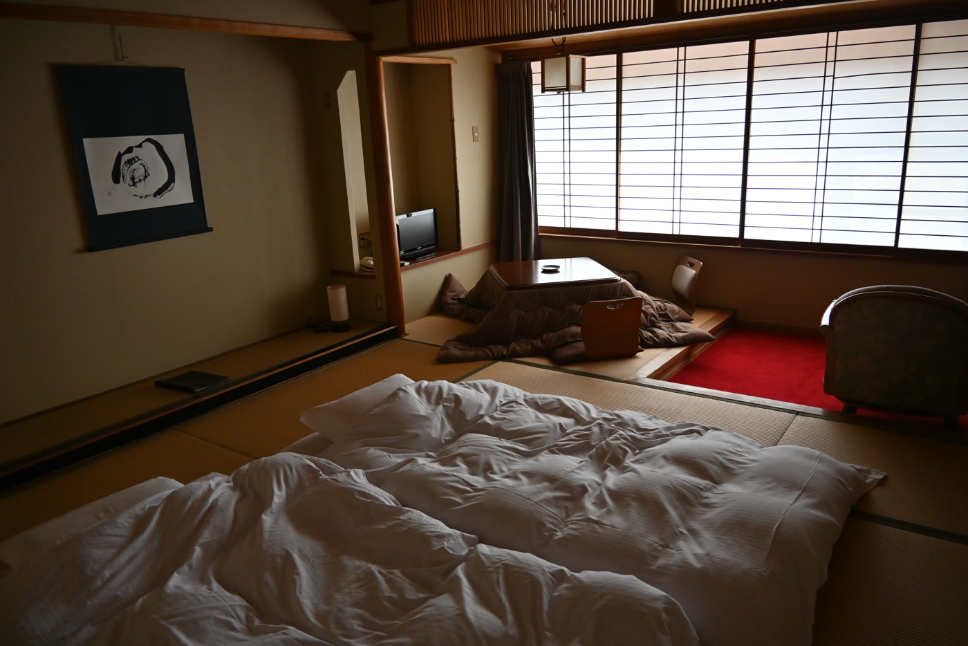Ryokan room with open futons, a kotatsu, and shoji windows