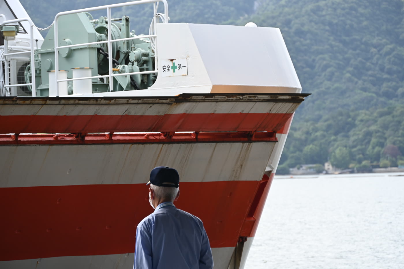 A man in a cap facing the bow of a docking ferry