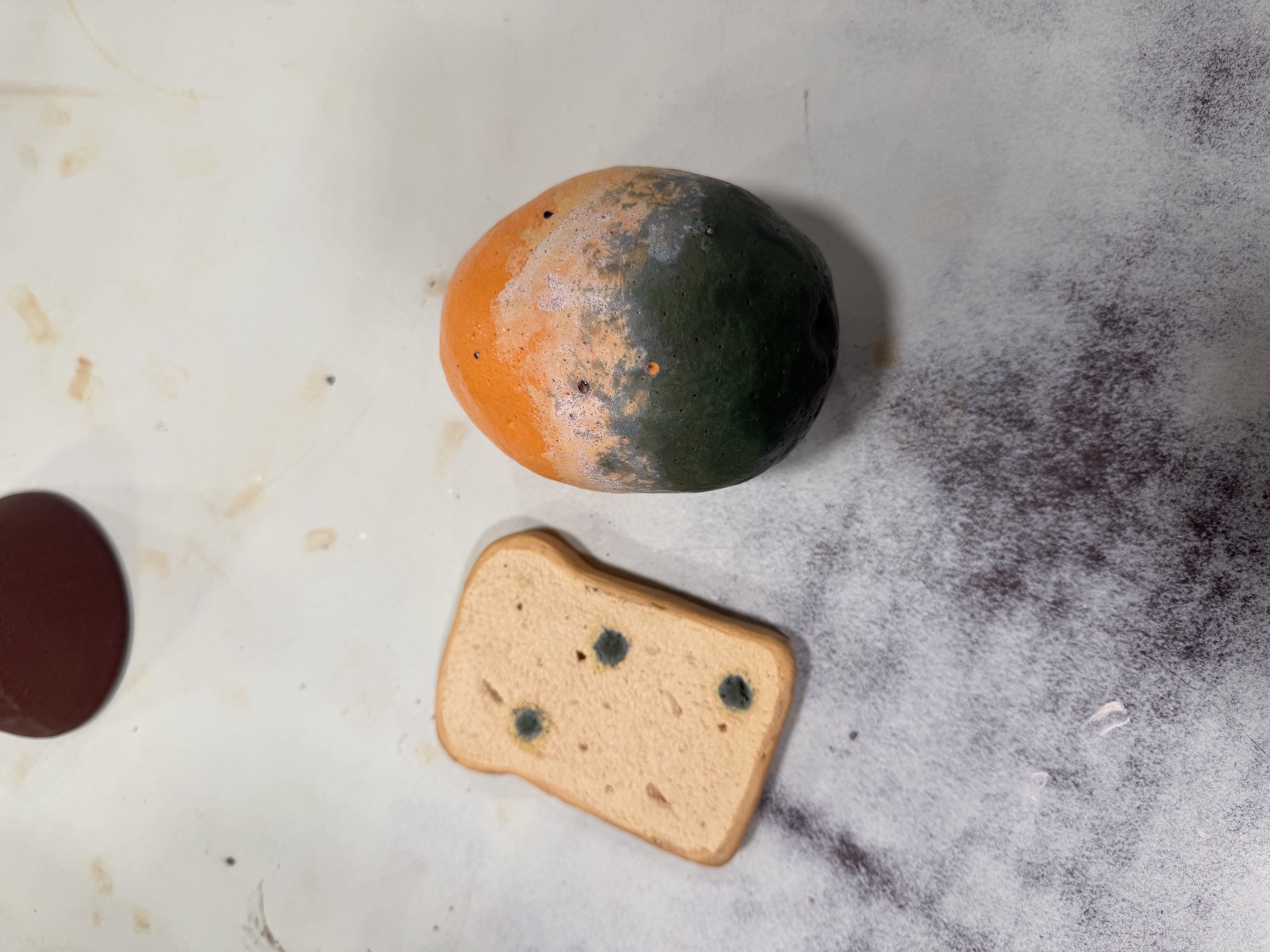Ceramic moldy orange and a slice of bread with mold spots